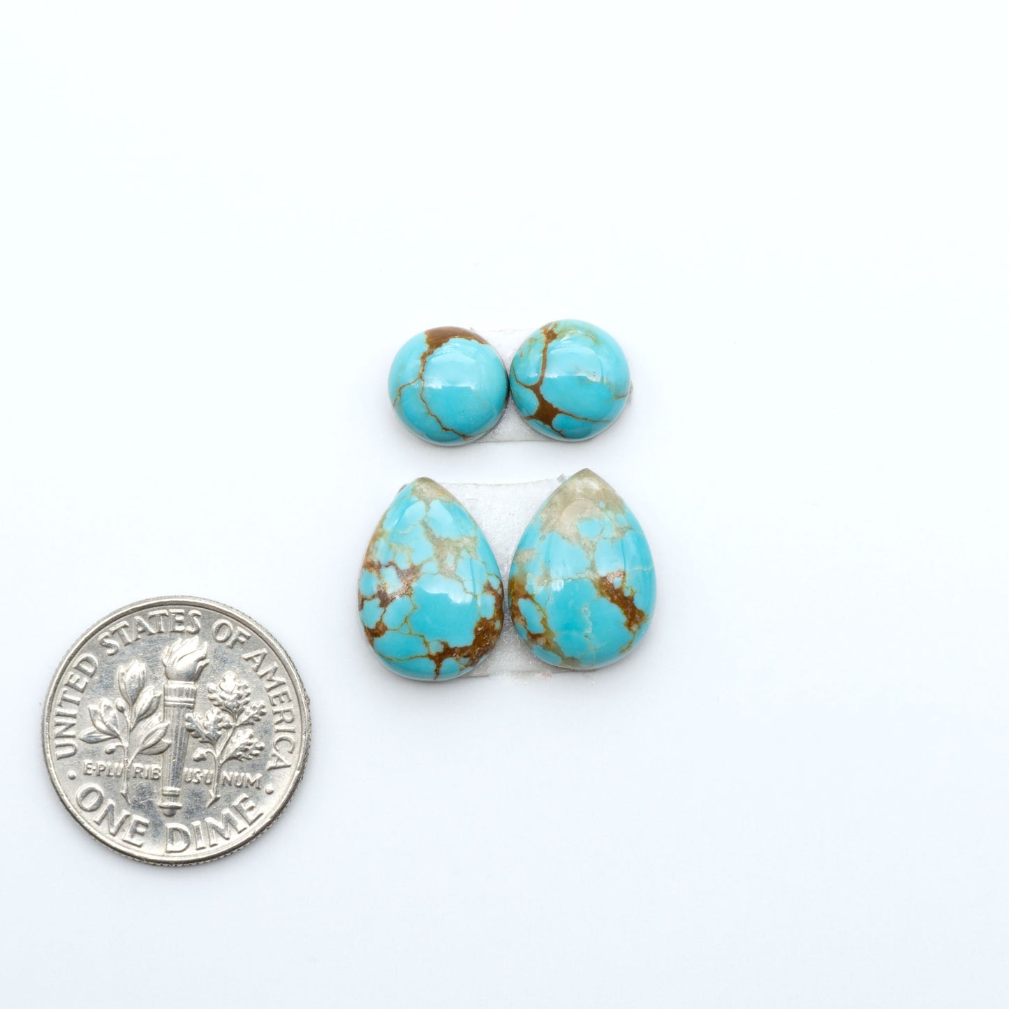 Number 8 Turquoise cabochons, blue and green color with brown matrix, polished stones on a white background, with a US dime for scale
