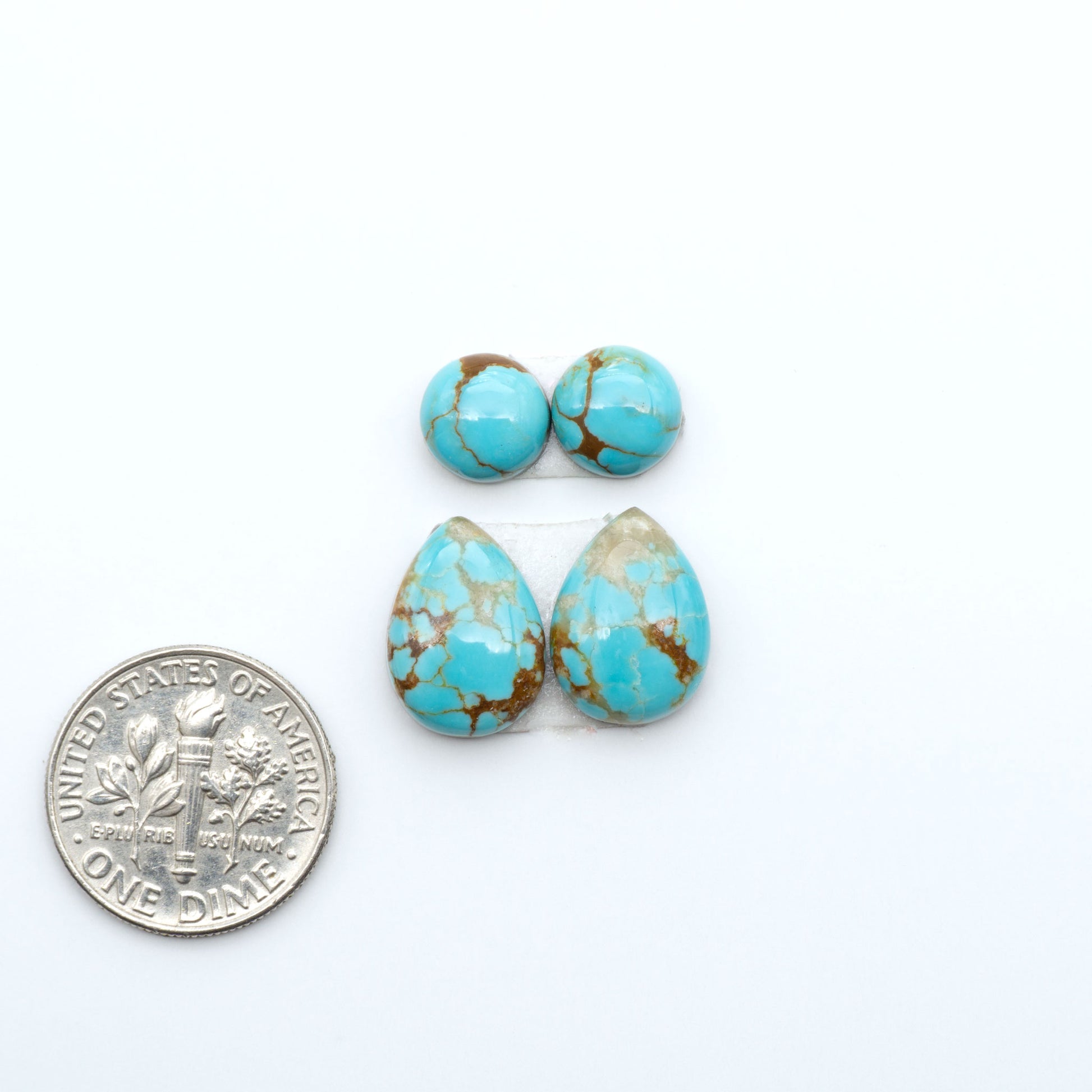 Number 8 Turquoise cabochons, blue and green color with brown matrix, polished stones on a white background, with a US dime for scale