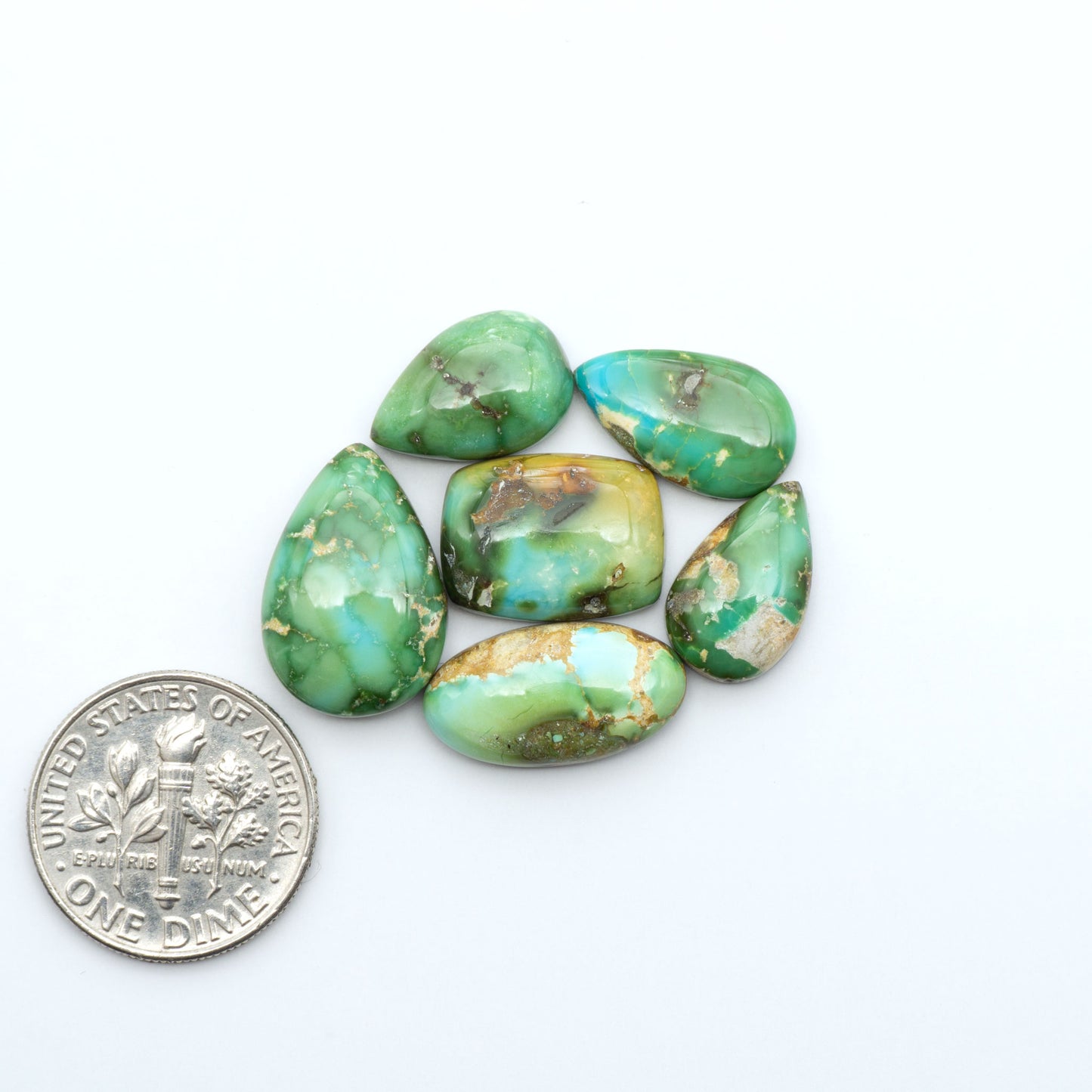 Sonoran Mountain Turquoise cabochons, blue-green color with natural matrix, polished stones on a white background, with a US dime for scale