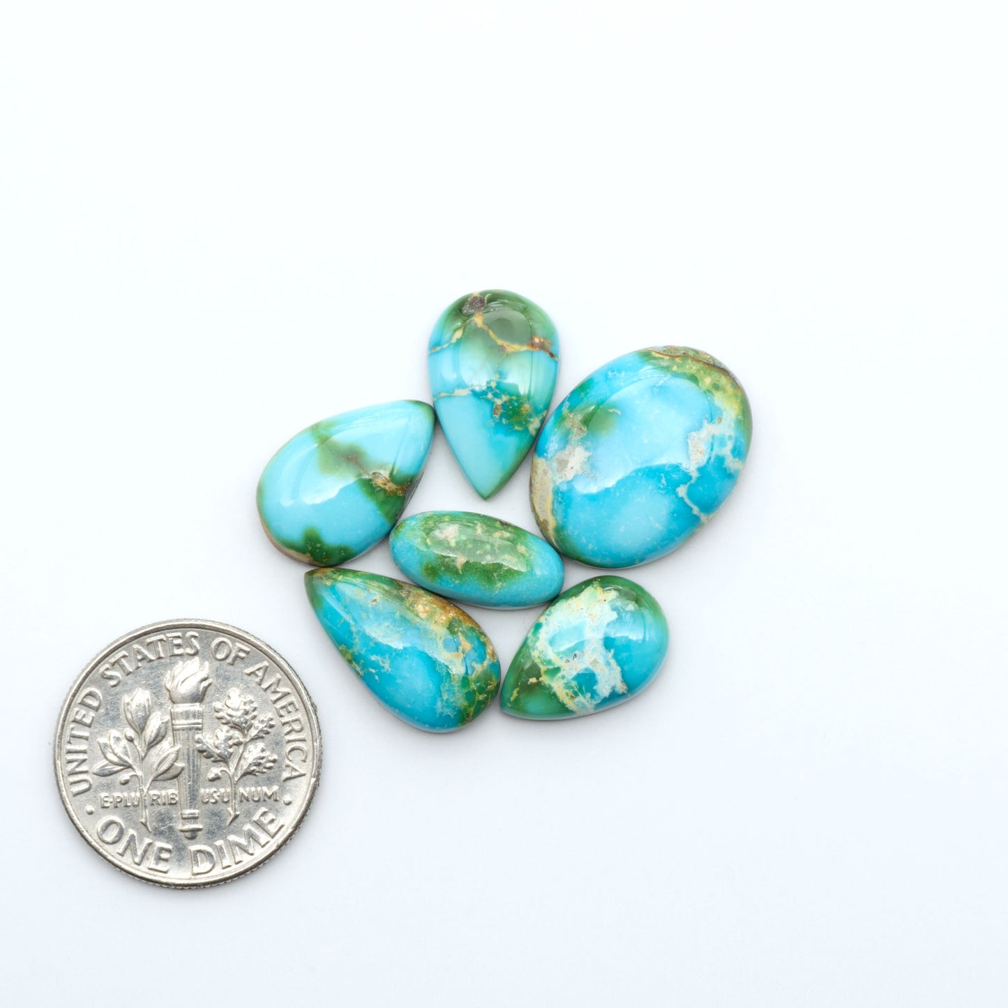 Sonoran Mountain Turquoise cabochons, blue-green color with natural matrix, polished stones on a white background, with a US dime for scale