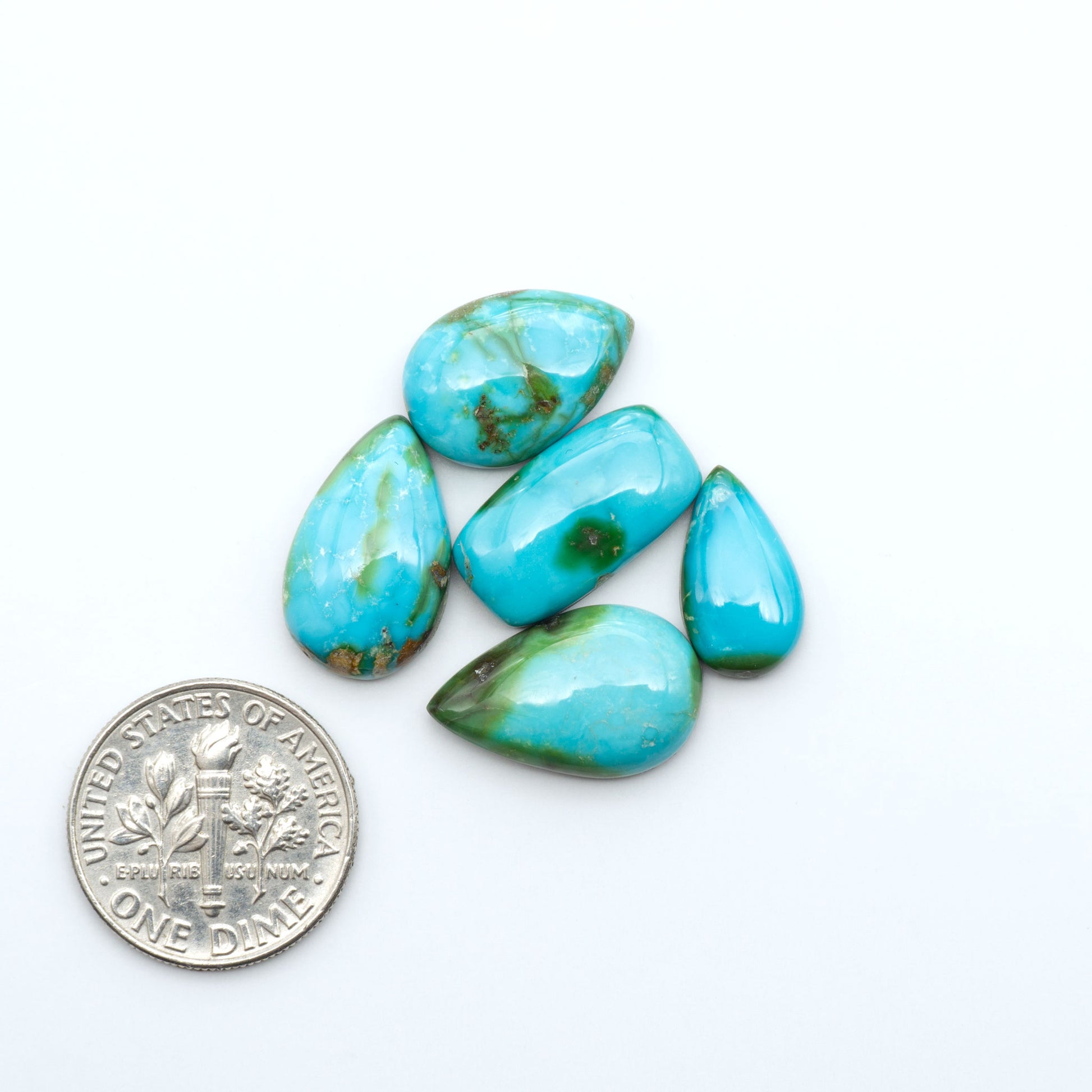 Sonoran Mountain Turquoise cabochons, blue-green color with natural matrix, polished stones on a white background, with a US dime for scale