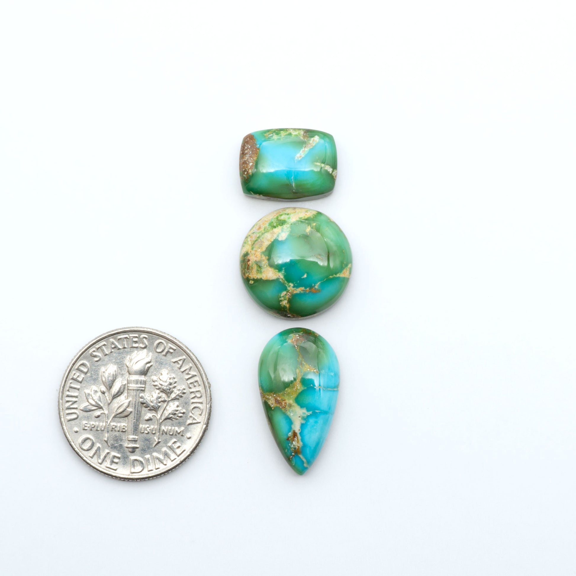 Sonoran Mountain Turquoise cabochons, blue-green color with natural matrix, polished stones on a white background, with a US dime for scale
