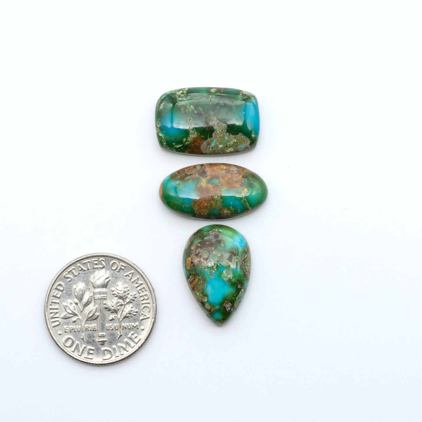 Sonoran Mountain Turquoise cabochons, blue-green color with natural matrix, polished stones on a white background, with a US dime for scale