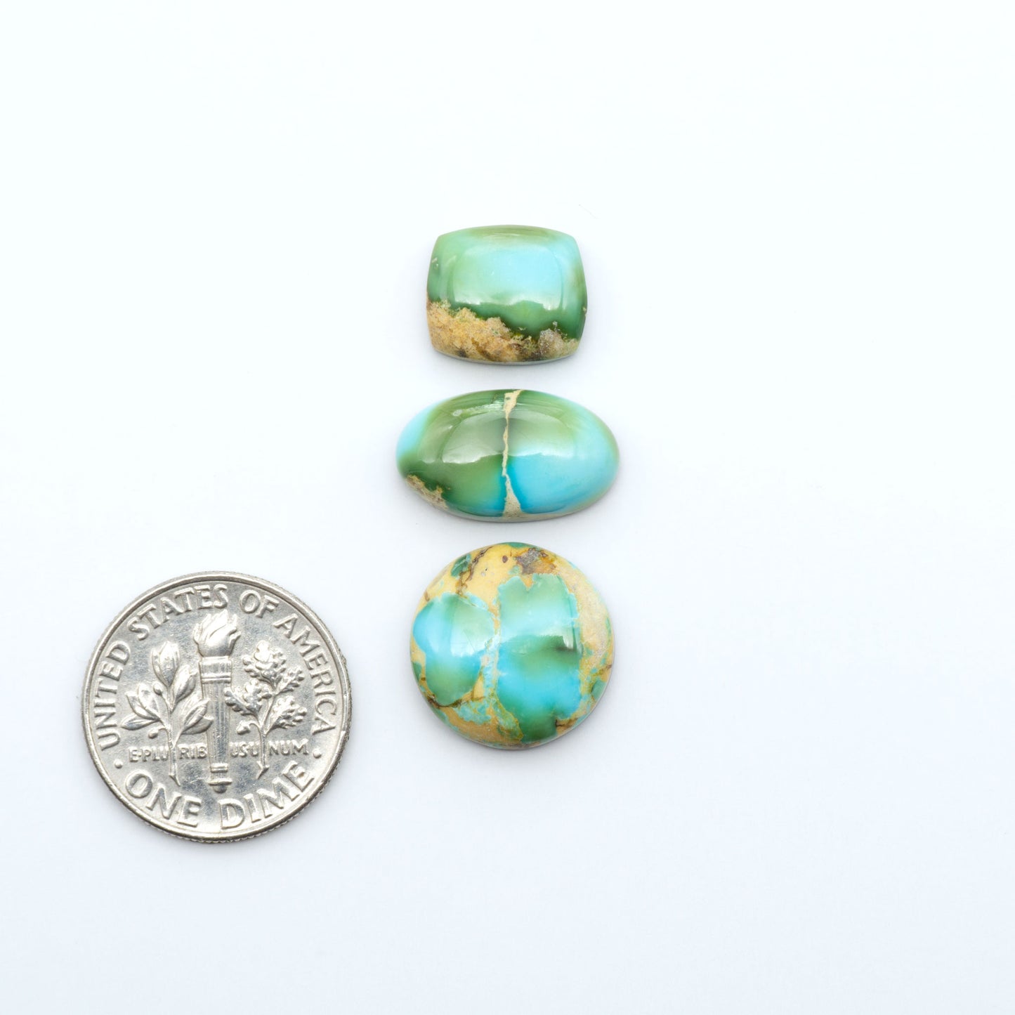Sonoran Mountain Turquoise cabochons, blue-green color with natural matrix, polished stones on a white background, with a US dime for scale