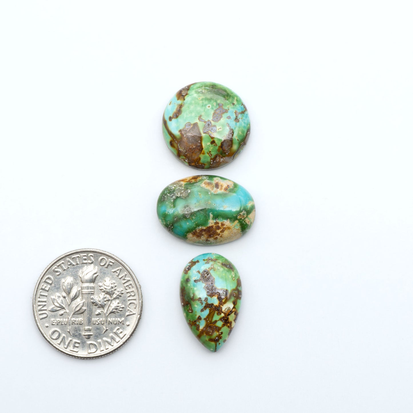 Sonoran Mountain Turquoise cabochons, blue-green color with natural matrix, polished stones on a white background, with a US dime for scale