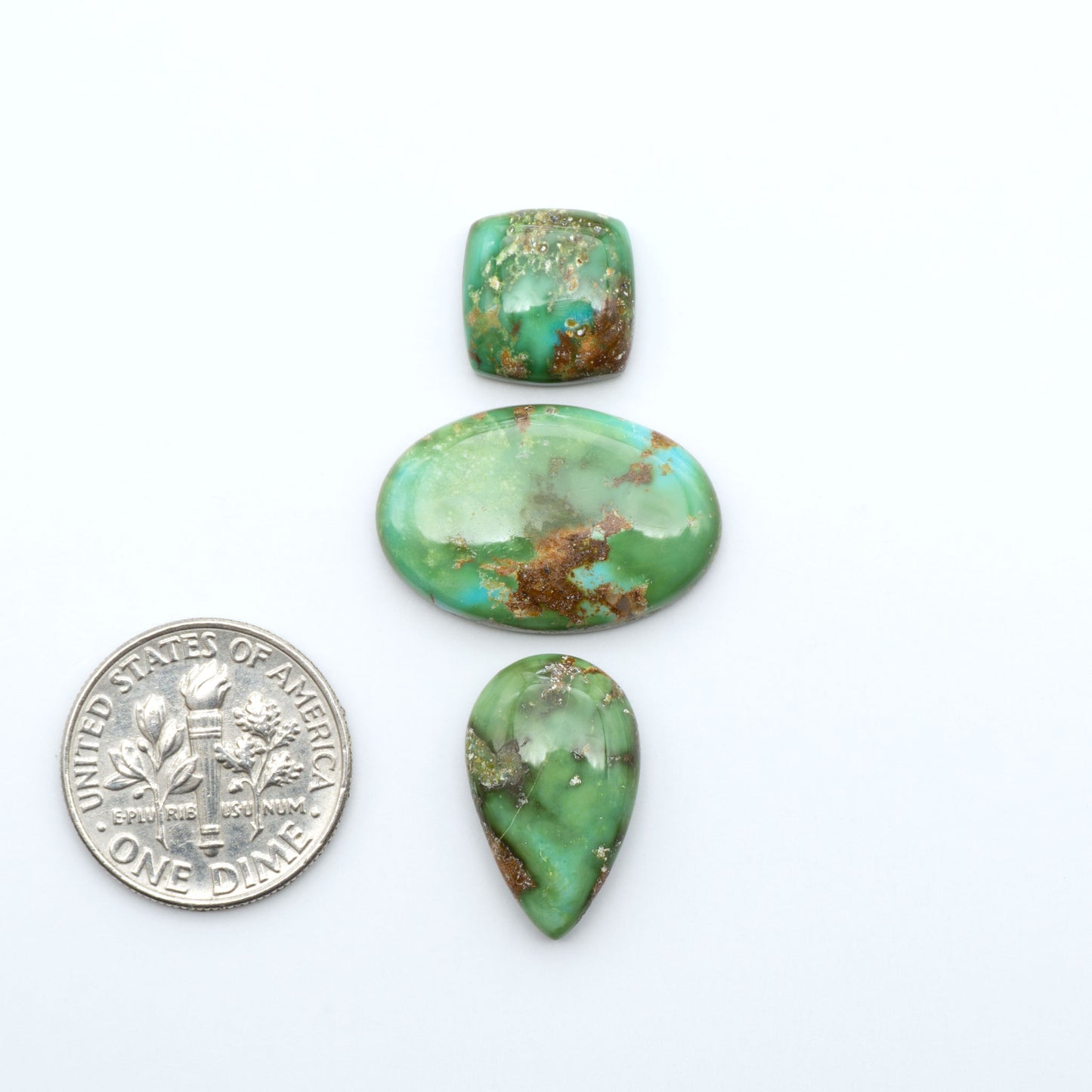 Sonoran Mountain Turquoise cabochons, blue-green color with natural matrix, polished stones on a white background, with a US dime for scale