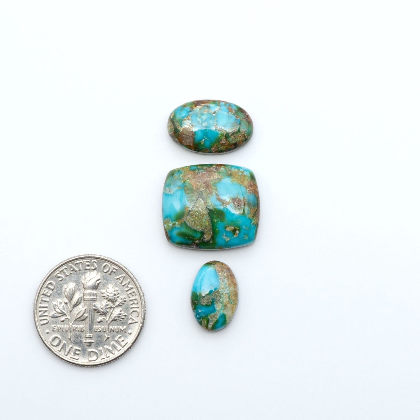 Sonoran Mountain Turquoise cabochons, blue-green color with natural matrix, polished stones on a white background, with a US dime for scale