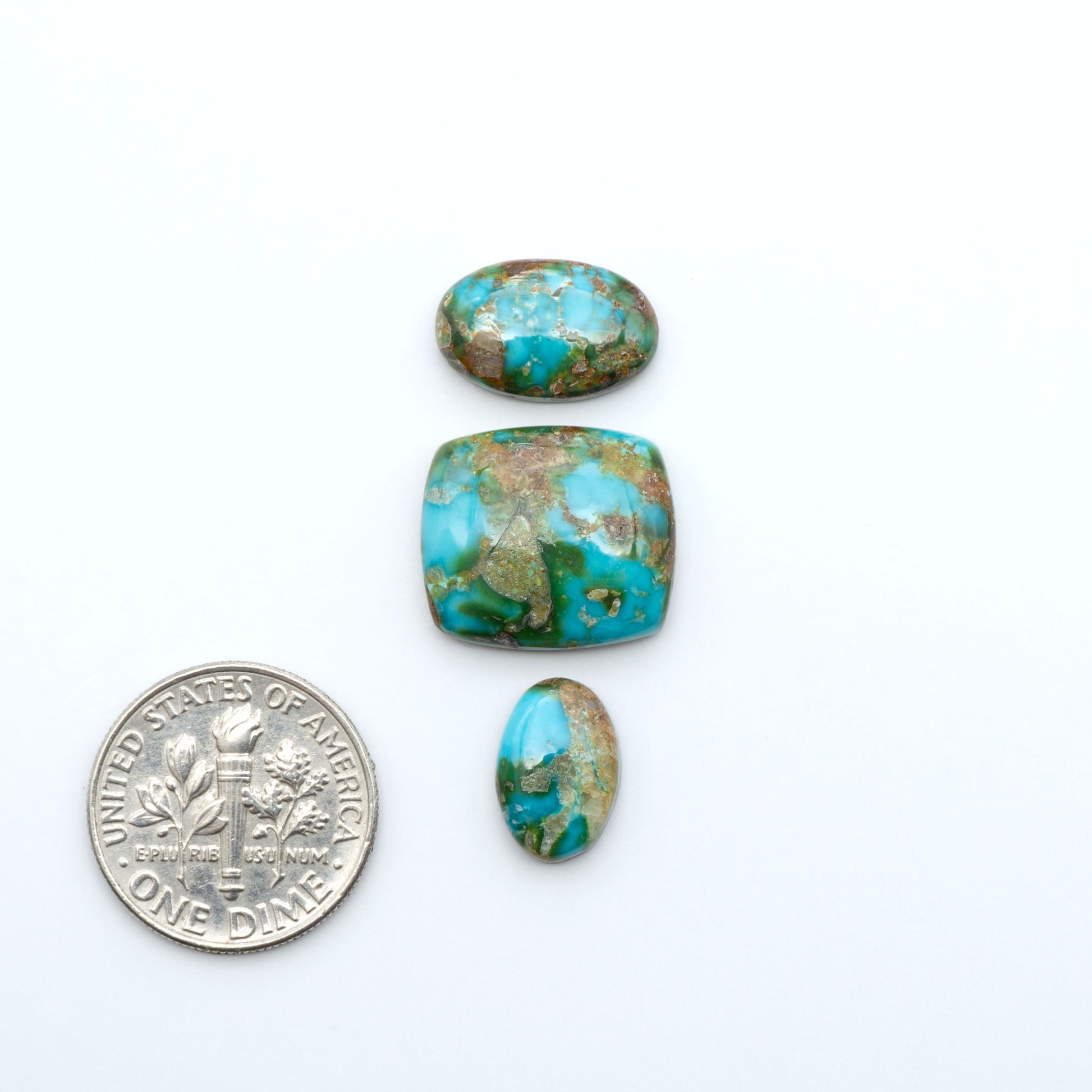 Sonoran Mountain Turquoise cabochons, blue-green color with natural matrix, polished stones on a white background, with a US dime for scale