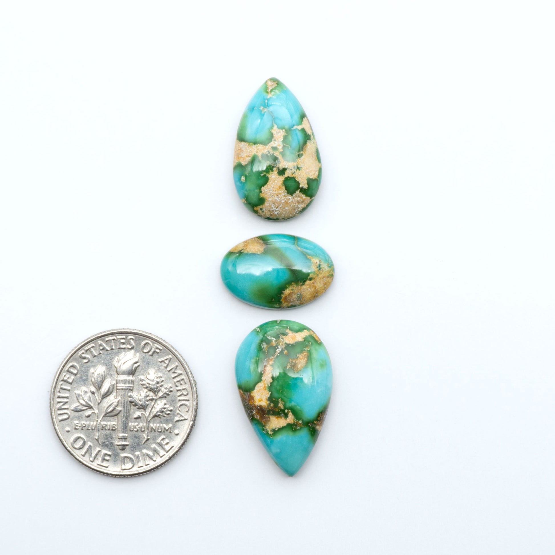 Sonoran Mountain Turquoise cabochons, blue-green color with natural matrix, polished stones on a white background, with a US dime for scale