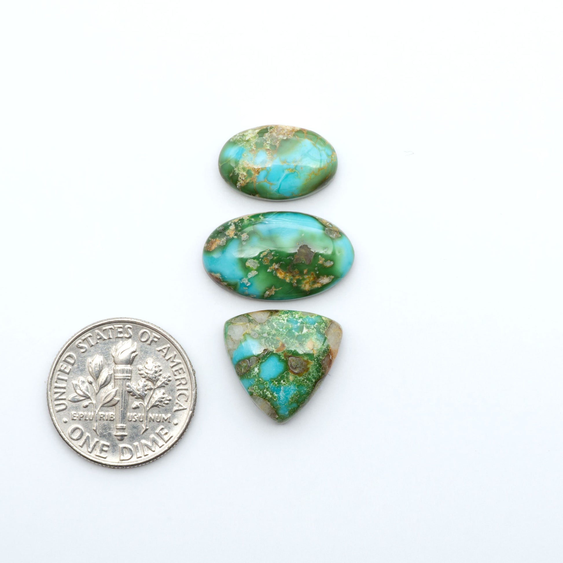 Sonoran Mountain Turquoise cabochons, blue-green color with natural matrix, polished stones on a white background, with a US dime for scale