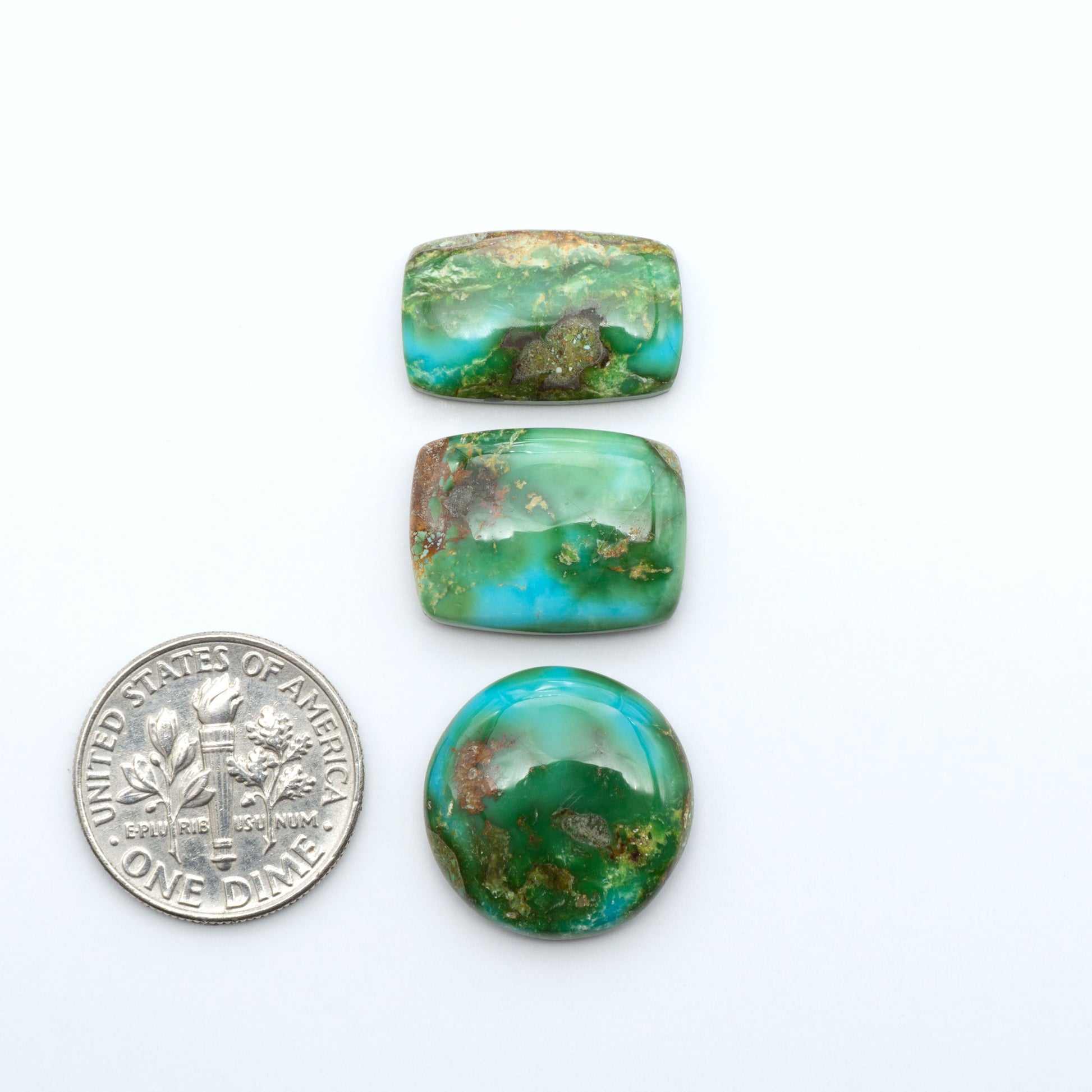 Sonoran Mountain Turquoise cabochons, blue-green color with natural matrix, polished stones on a white background, with a US dime for scale