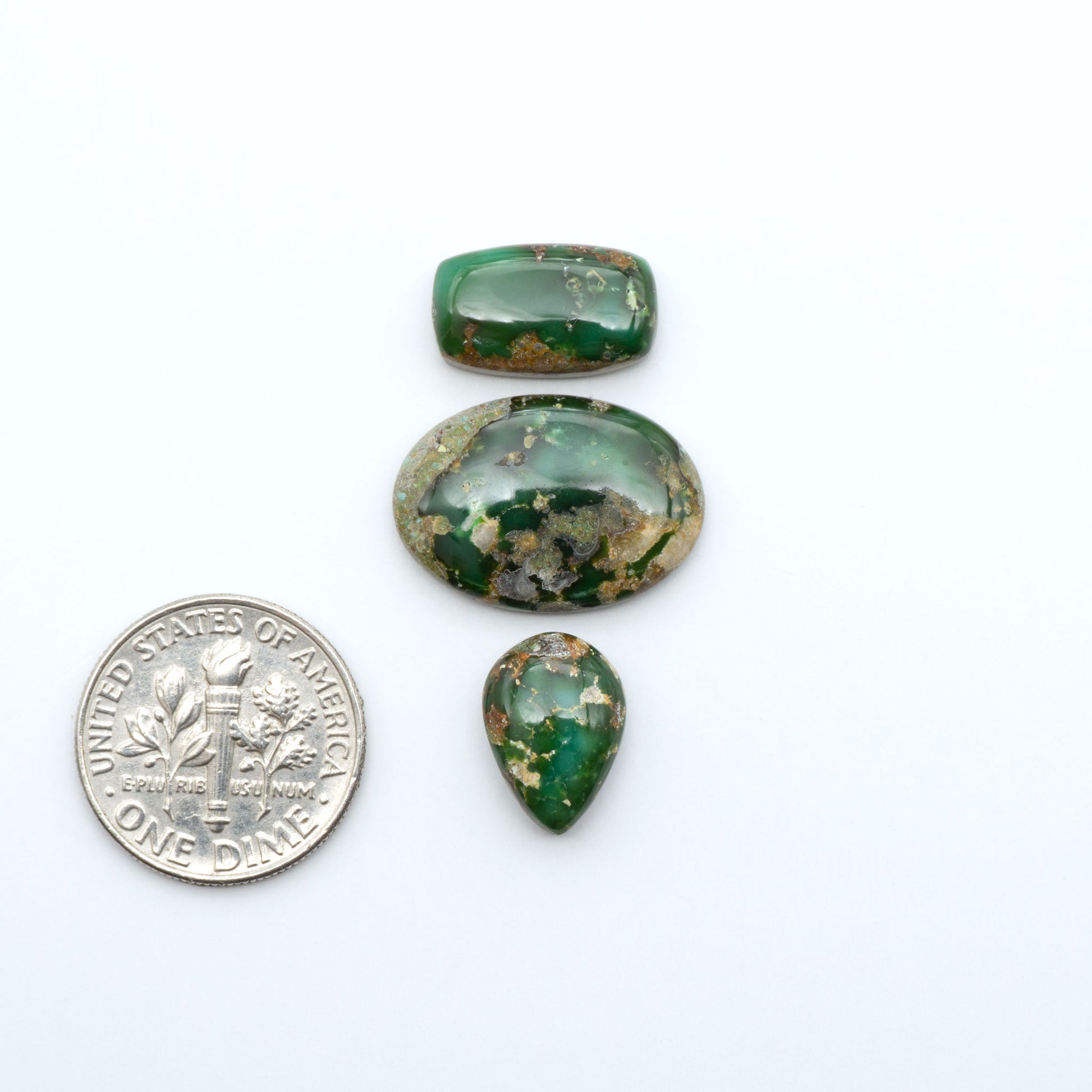 Sonoran Mountain Turquoise cabochons, blue-green color with natural matrix, polished stones on a white background, with a US dime for scale