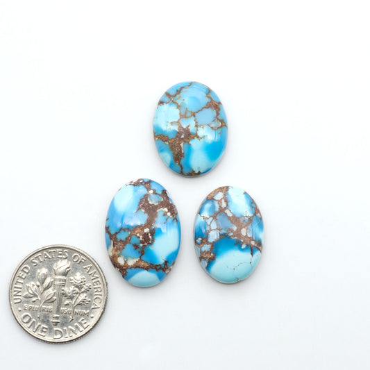 Golden Hills Turquoise cabochons, icy blue to lavender tones with chocolate matrix, polished stones on a white background with a US dime for scale