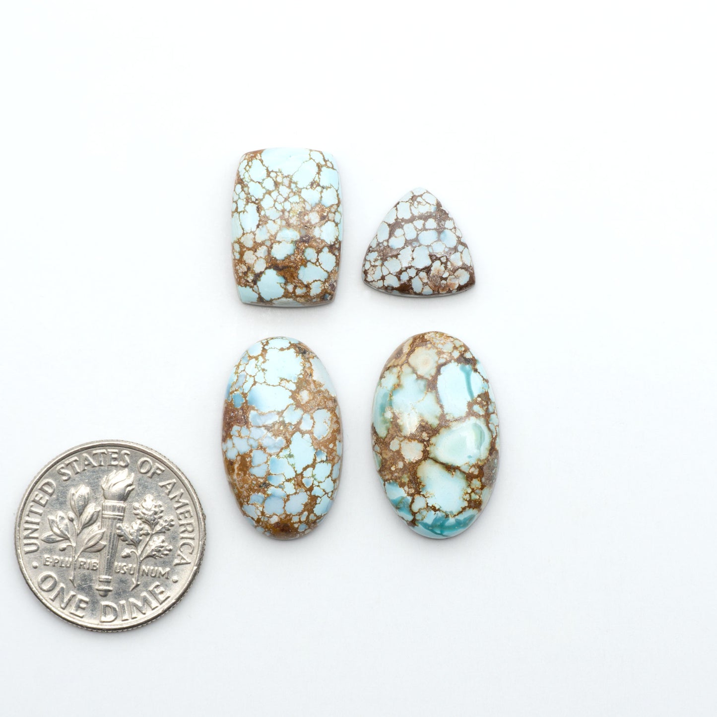 Golden Hills Turquoise cabochons, icy blue to lavender tones with chocolate matrix, polished stones on a white background with a US dime for scale