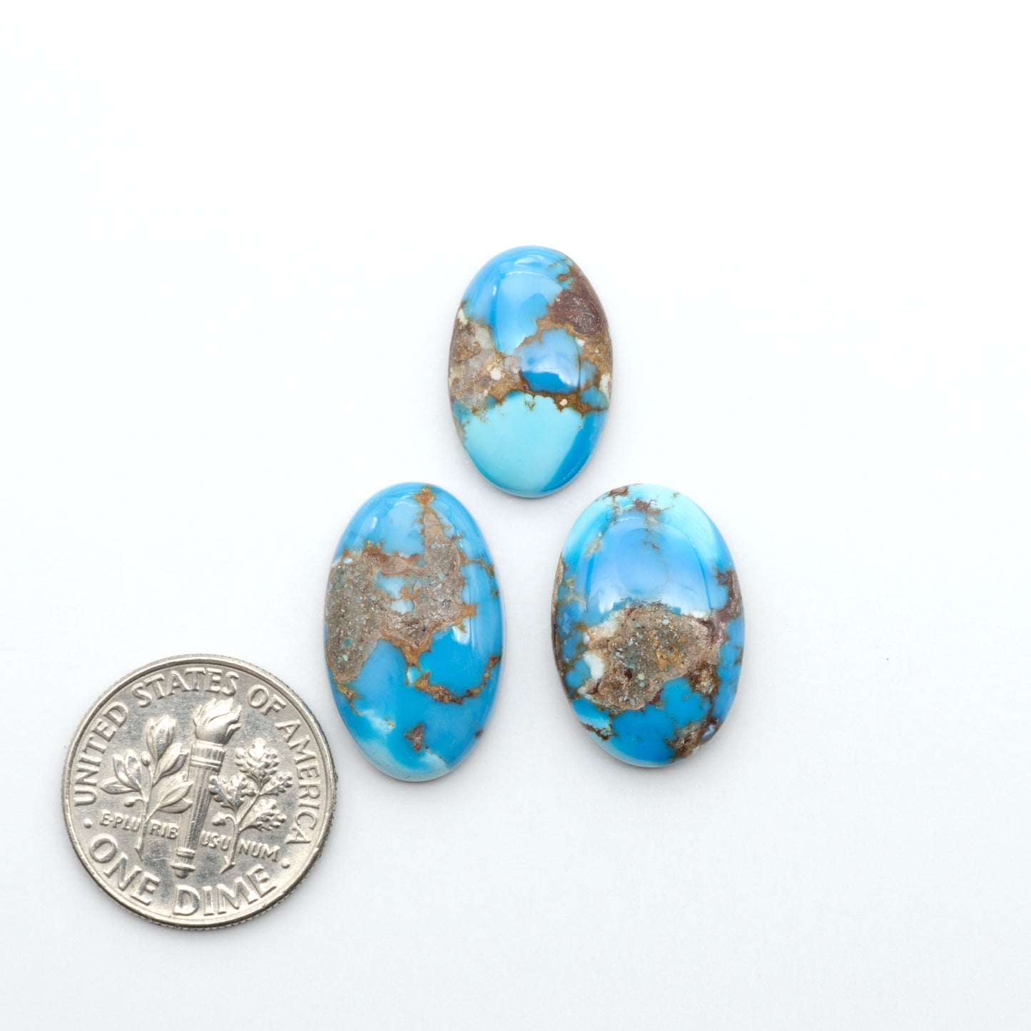 Golden Hills Turquoise cabochons, icy blue to lavender tones with chocolate matrix, polished stones on a white background with a US dime for scale