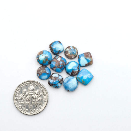 Golden Hills Turquoise cabochons, icy blue to lavender tones with chocolate matrix, polished stones on a white background with a US dime for scale