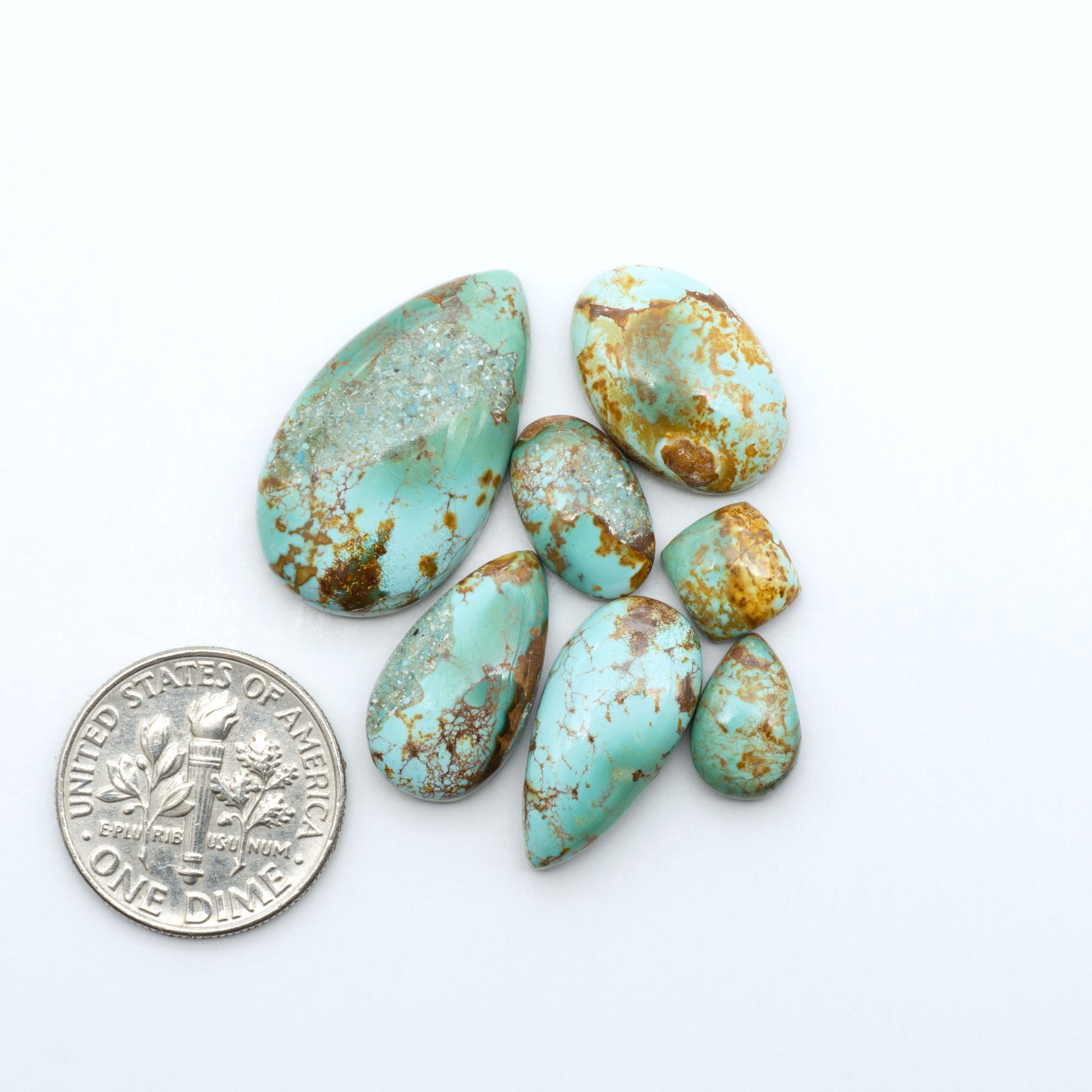 Royston Turquoise cabochons, blue-green color with natural matrix, polished stones on a white background, with a US dime for scale