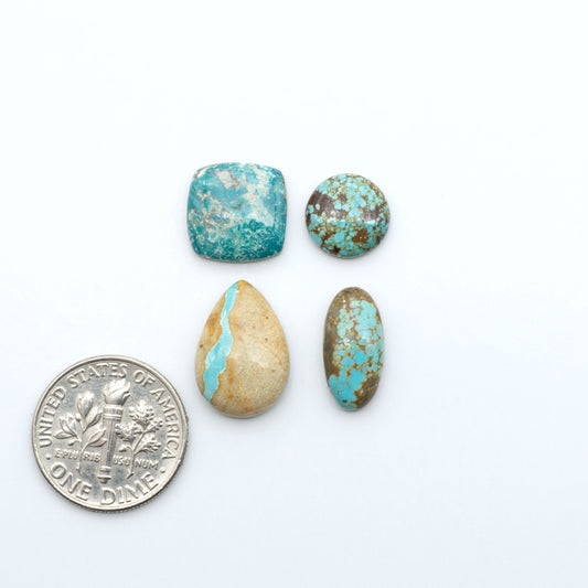 Assorted turquoise cabochon gemstones with varied colors and matrix on a white background with a US dime for scale
