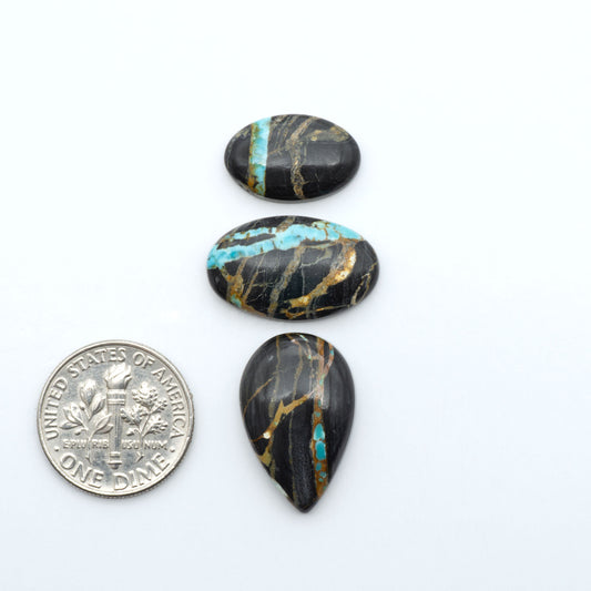 Black Jack turquoise cabochons, blue-green color with black matrix, polished stones on a white background with a US dime for scale
