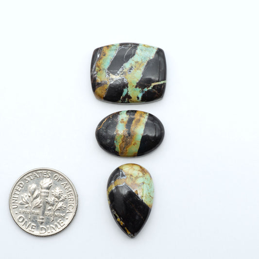Black Jack turquoise cabochons, blue-green color with black matrix, polished stones on a white background with a US dime for scale