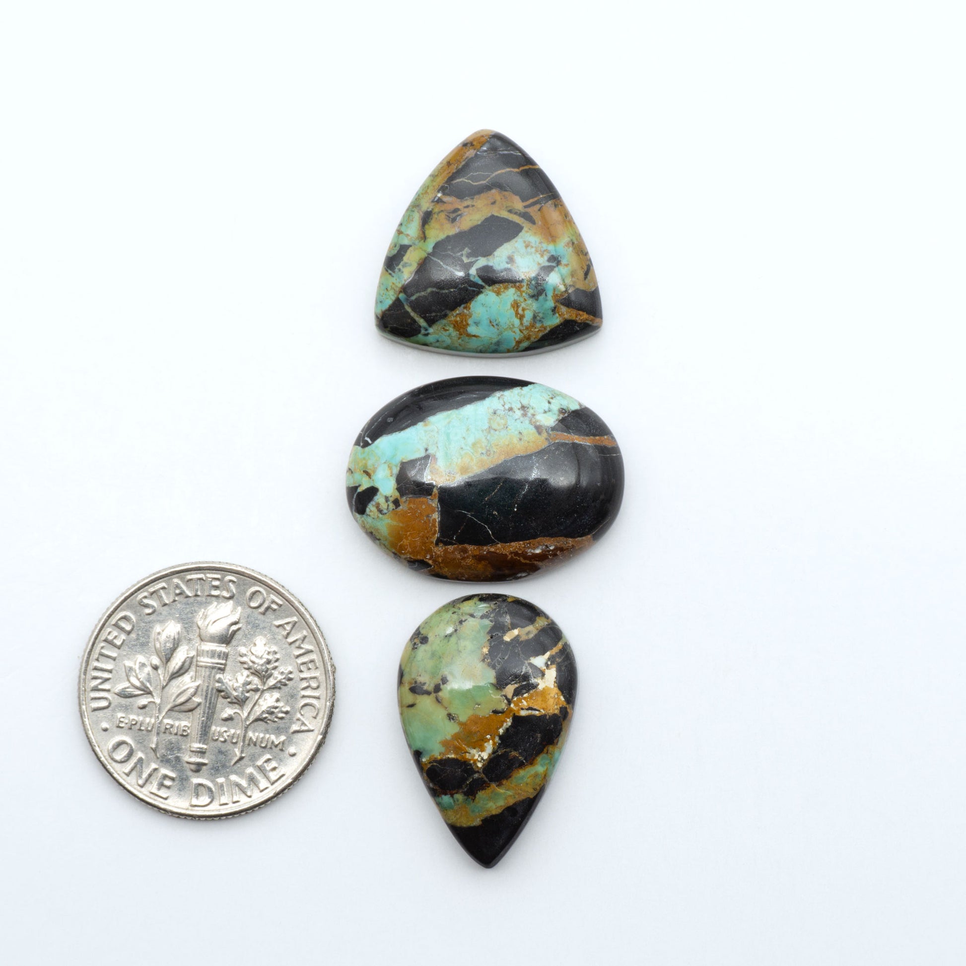 Black Jack turquoise cabochons, blue-green color with black matrix, polished stones on a white background with a US dime for scale