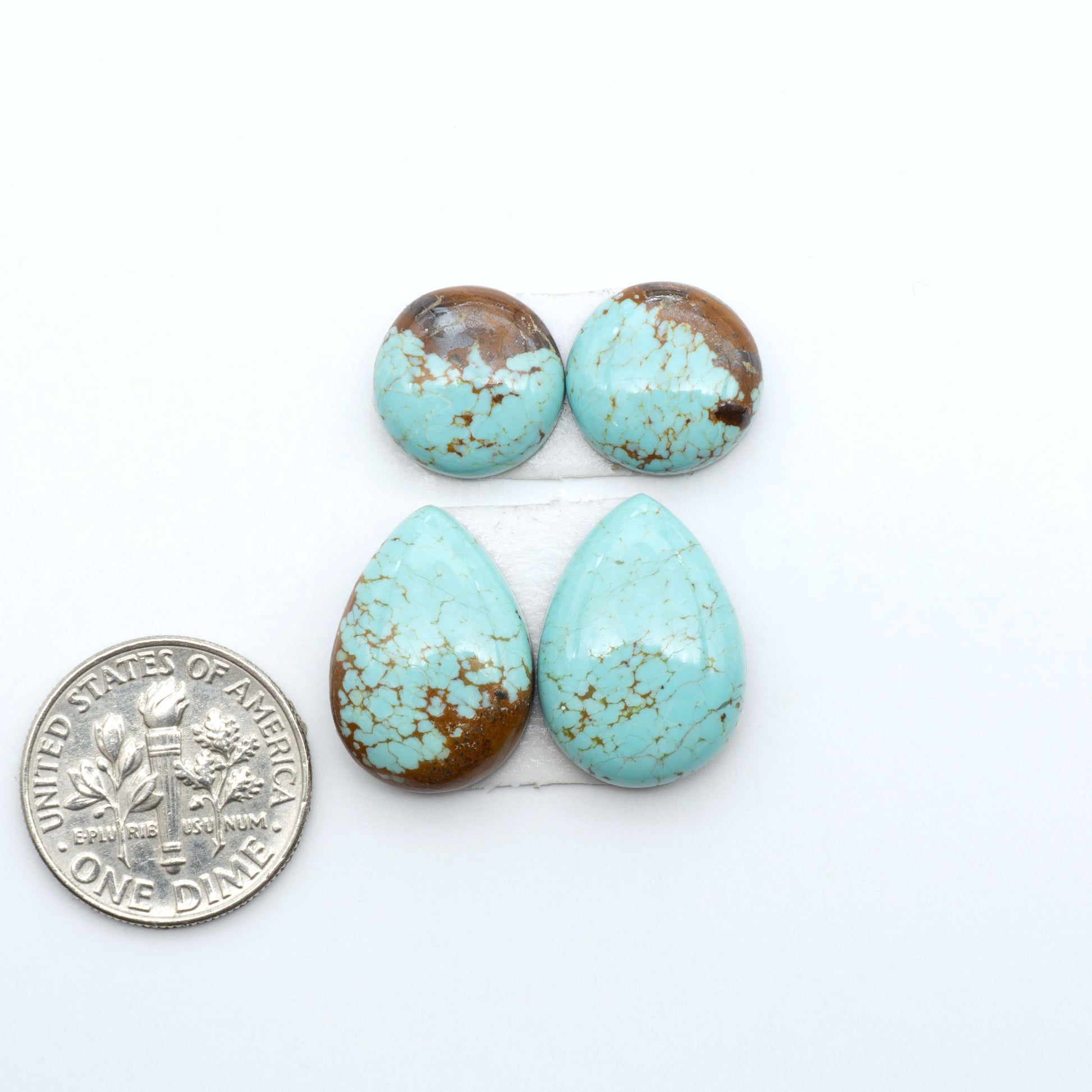 Number 8 Turquoise cabochons, blue and green color with brown matrix, polished stones on a white background, with a US dime for scale