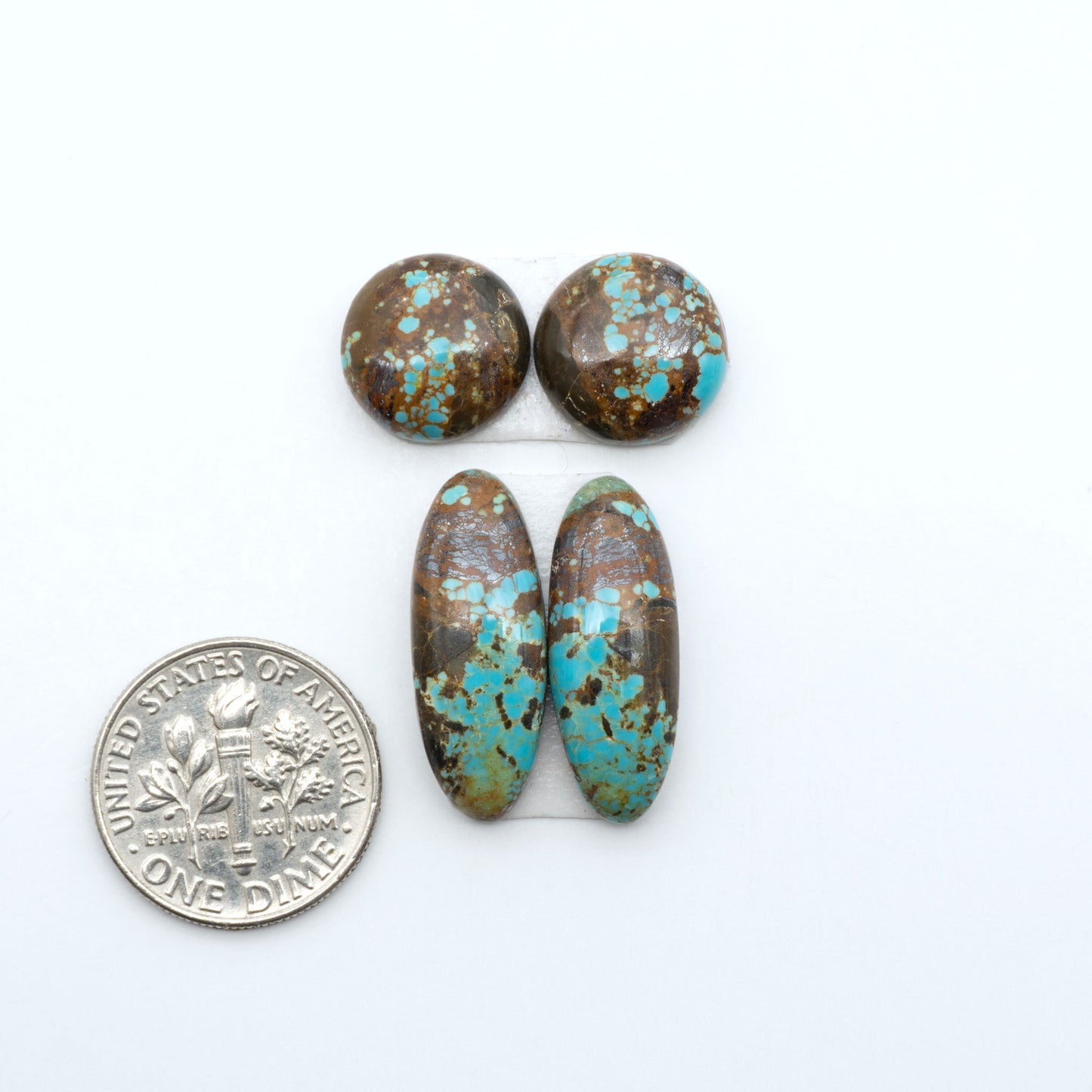 Number 8 Turquoise cabochons, blue and green color with brown matrix, polished stones on a white background, with a US dime for scale