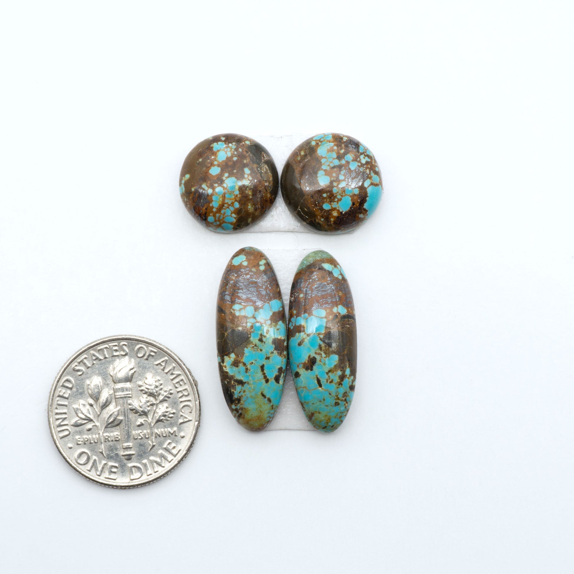 Number 8 Turquoise cabochons, blue and green color with brown matrix, polished stones on a white background, with a US dime for scale