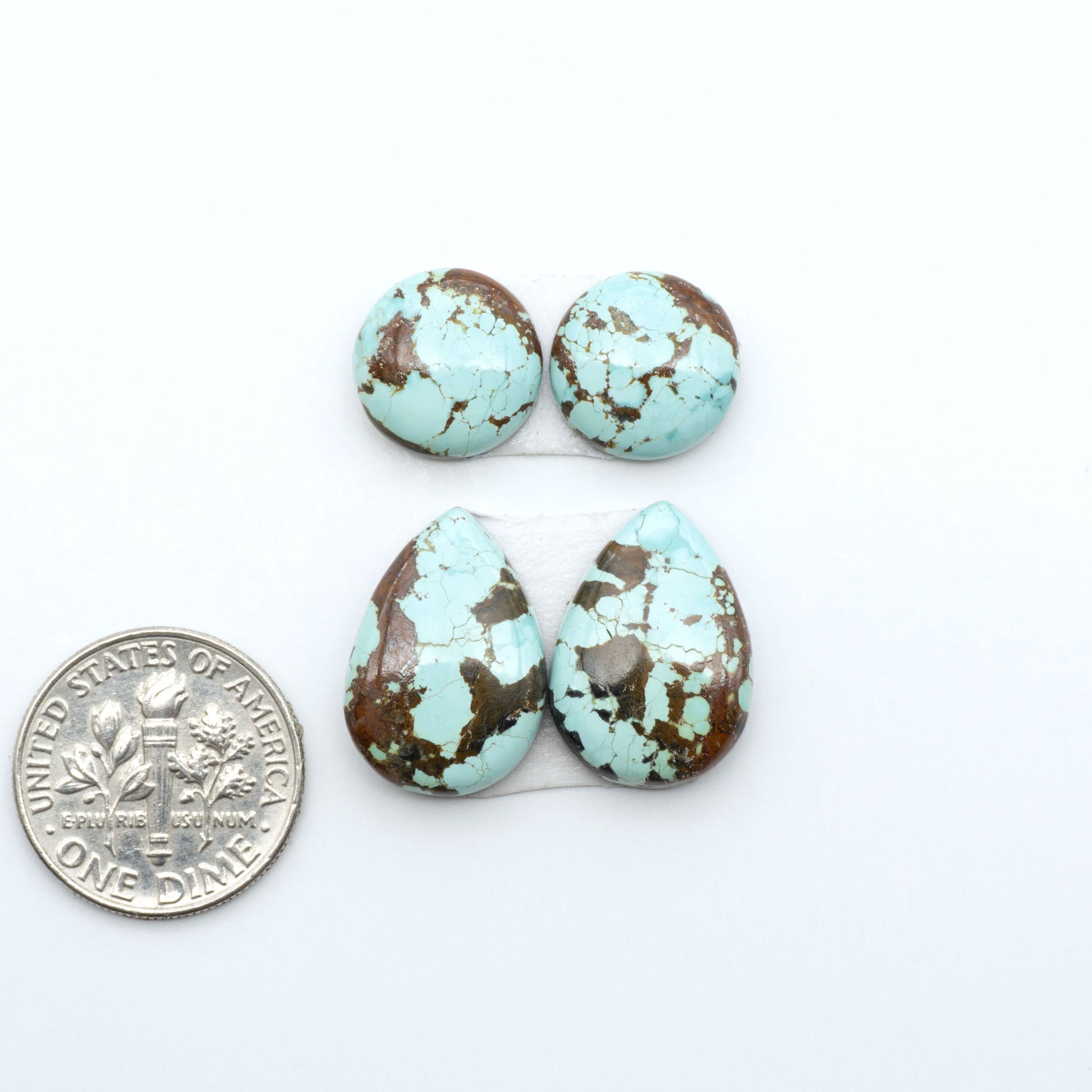 Number 8 Turquoise cabochons, blue and green color with brown matrix, polished stones on a white background, with a US dime for scale