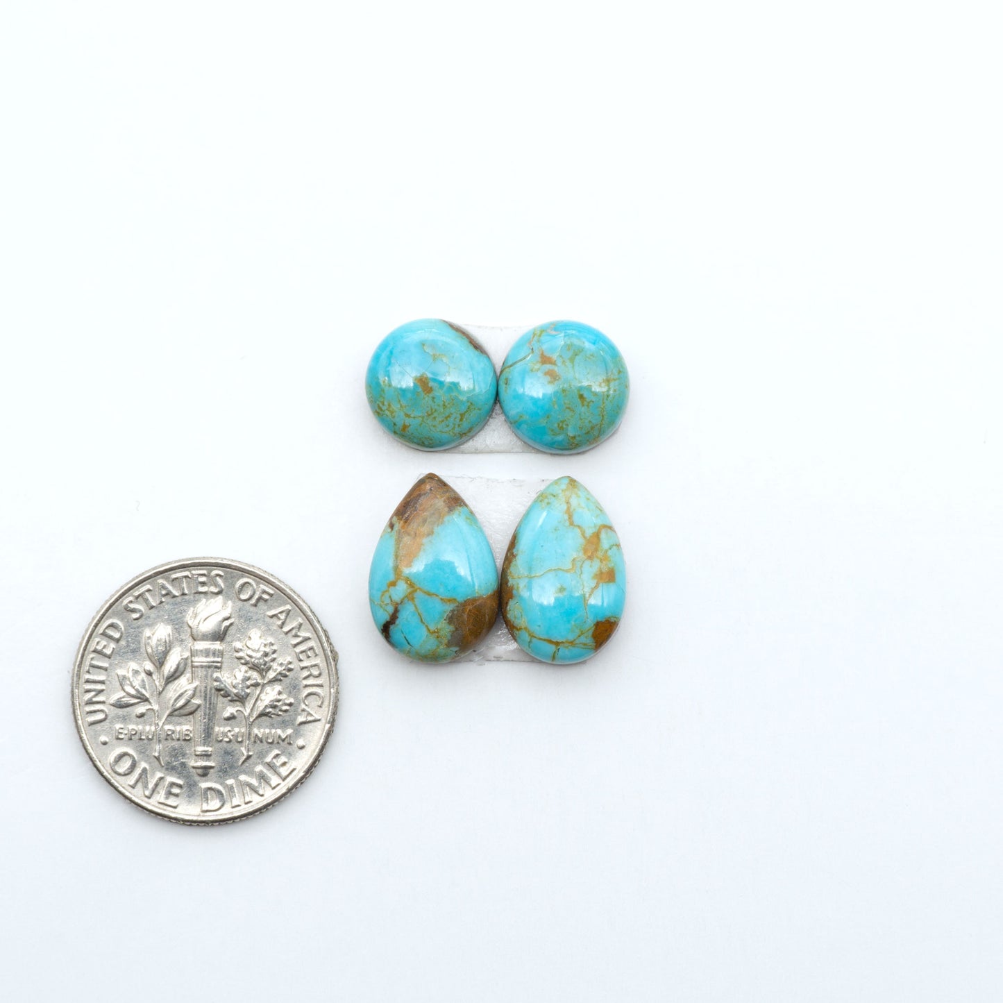 Number 8 Turquoise cabochons, blue and green color with brown matrix, polished stones on a white background, with a US dime for scale
