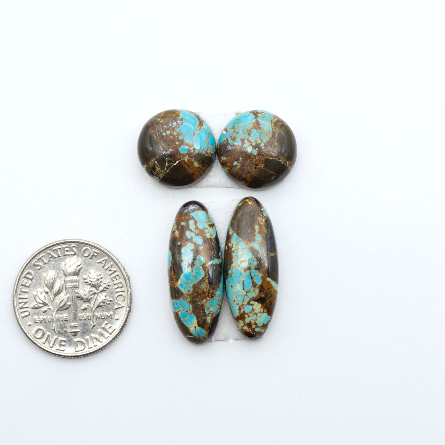 Number 8 Turquoise cabochons, blue and green color with brown matrix, polished stones on a white background, with a US dime for scale