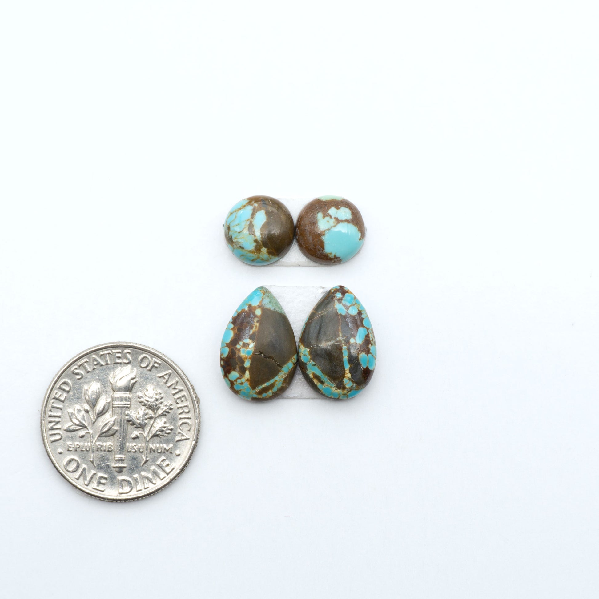 Number 8 Turquoise cabochons, blue and green color with brown matrix, polished stones on a white background, with a US dime for scale