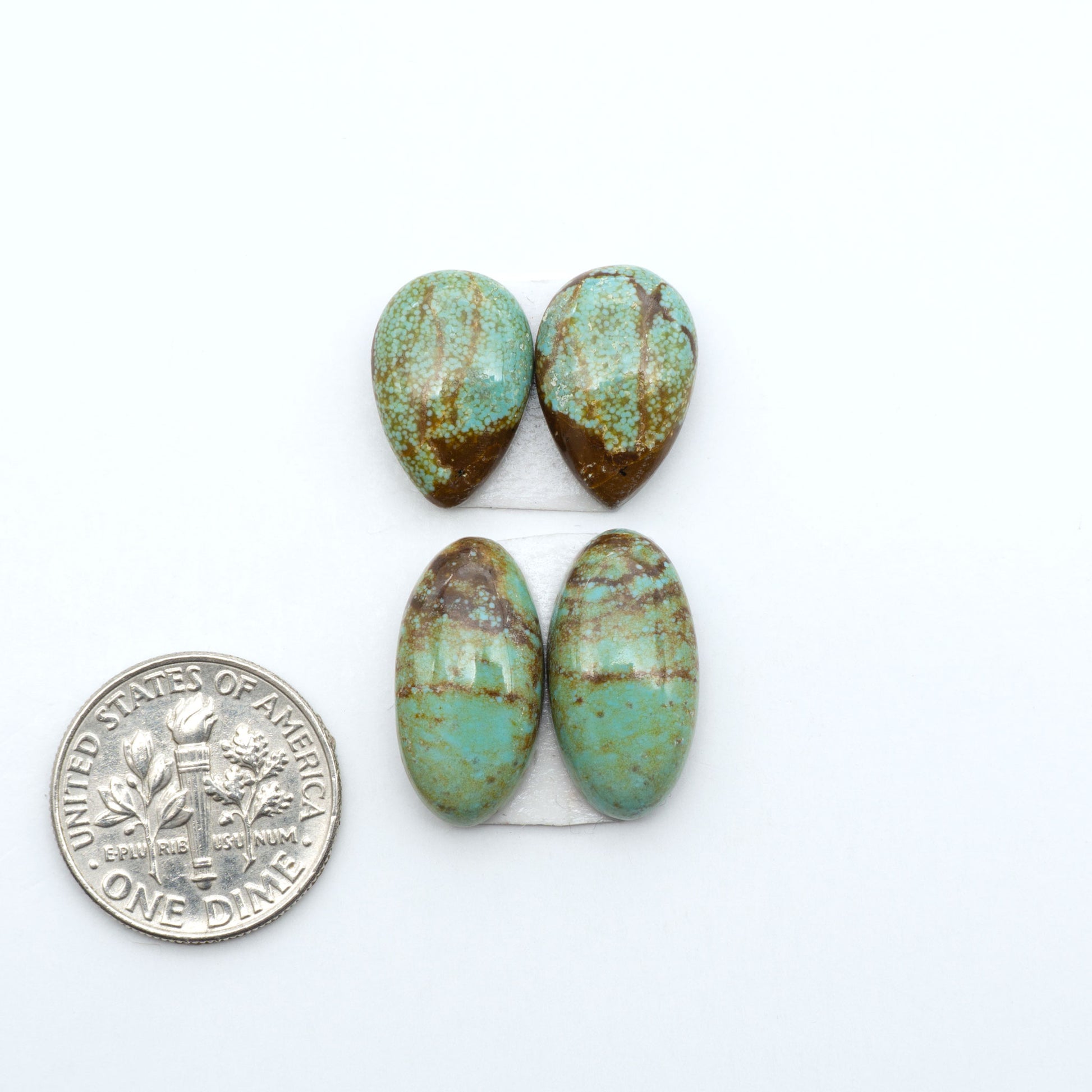 Number 8 Turquoise cabochons, blue and green color with brown matrix, polished stones on a white background, with a US dime for scale