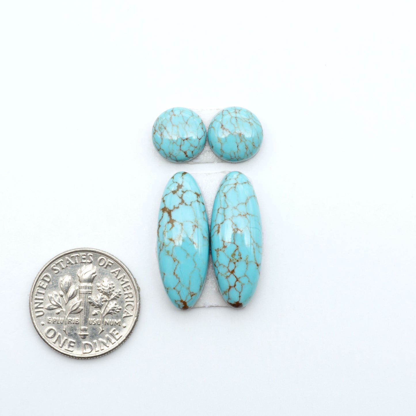Number 8 Turquoise cabochons, blue and green color with brown matrix, polished stones on a white background, with a US dime for scale