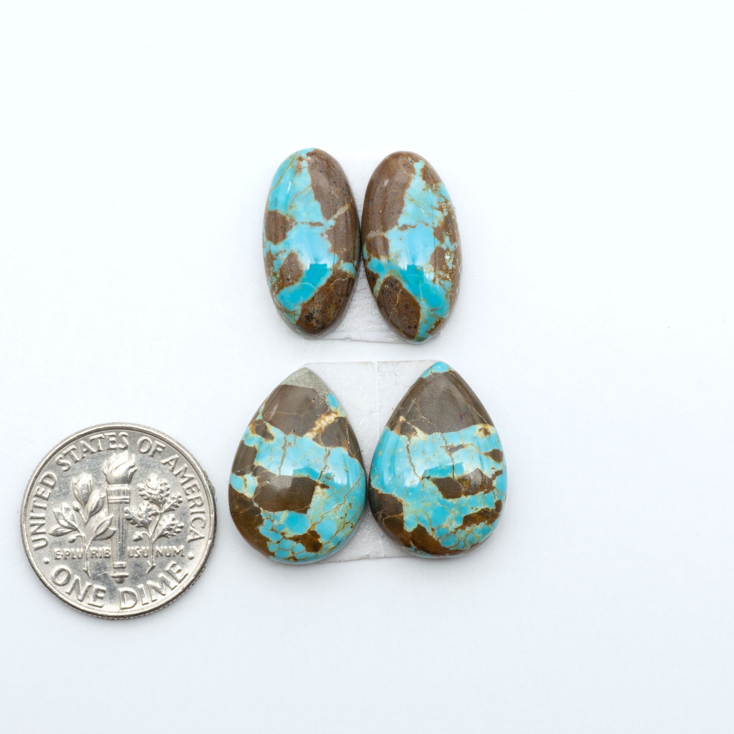 Number 8 Turquoise cabochons, blue and green color with brown matrix, polished stones on a white background, with a US dime for scale