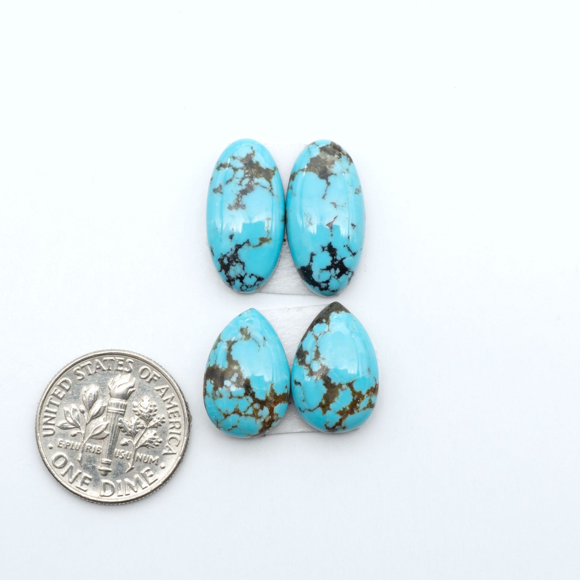 Number 8 Turquoise cabochons, blue and green color with brown matrix, polished stones on a white background, with a US dime for scale
