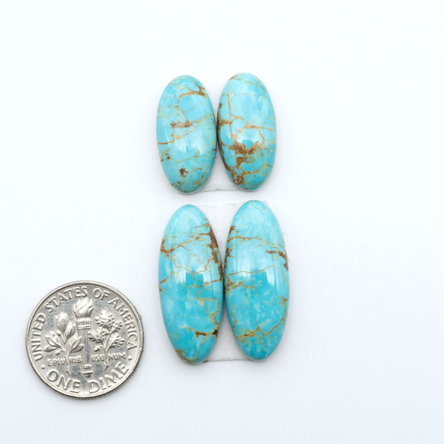 Number 8 Turquoise cabochons, blue and green color with brown matrix, polished stones on a white background, with a US dime for scale