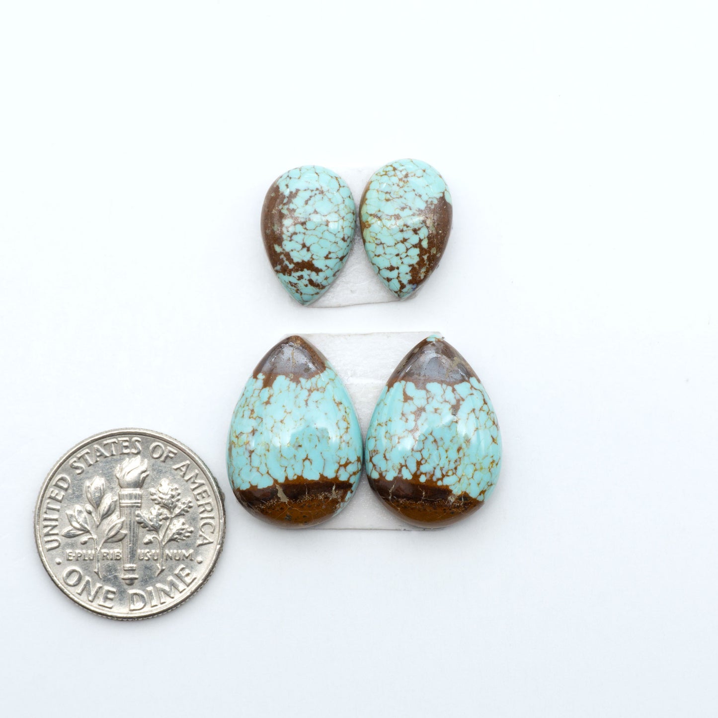 Number 8 Turquoise cabochons, blue and green color with brown matrix, polished stones on a white background, with a US dime for scale