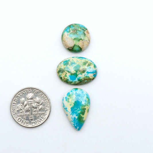 Sonoran Mountain Turquoise cabochons, blue-green color with natural matrix, polished stones on a white background, with a US dime for scale