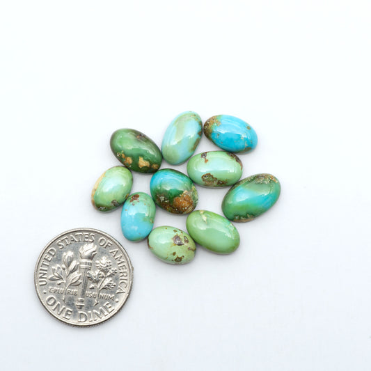 Sonoran Mountain Turquoise cabochons, blue-green color with natural matrix, polished stones on a white background, with a US dime for scale