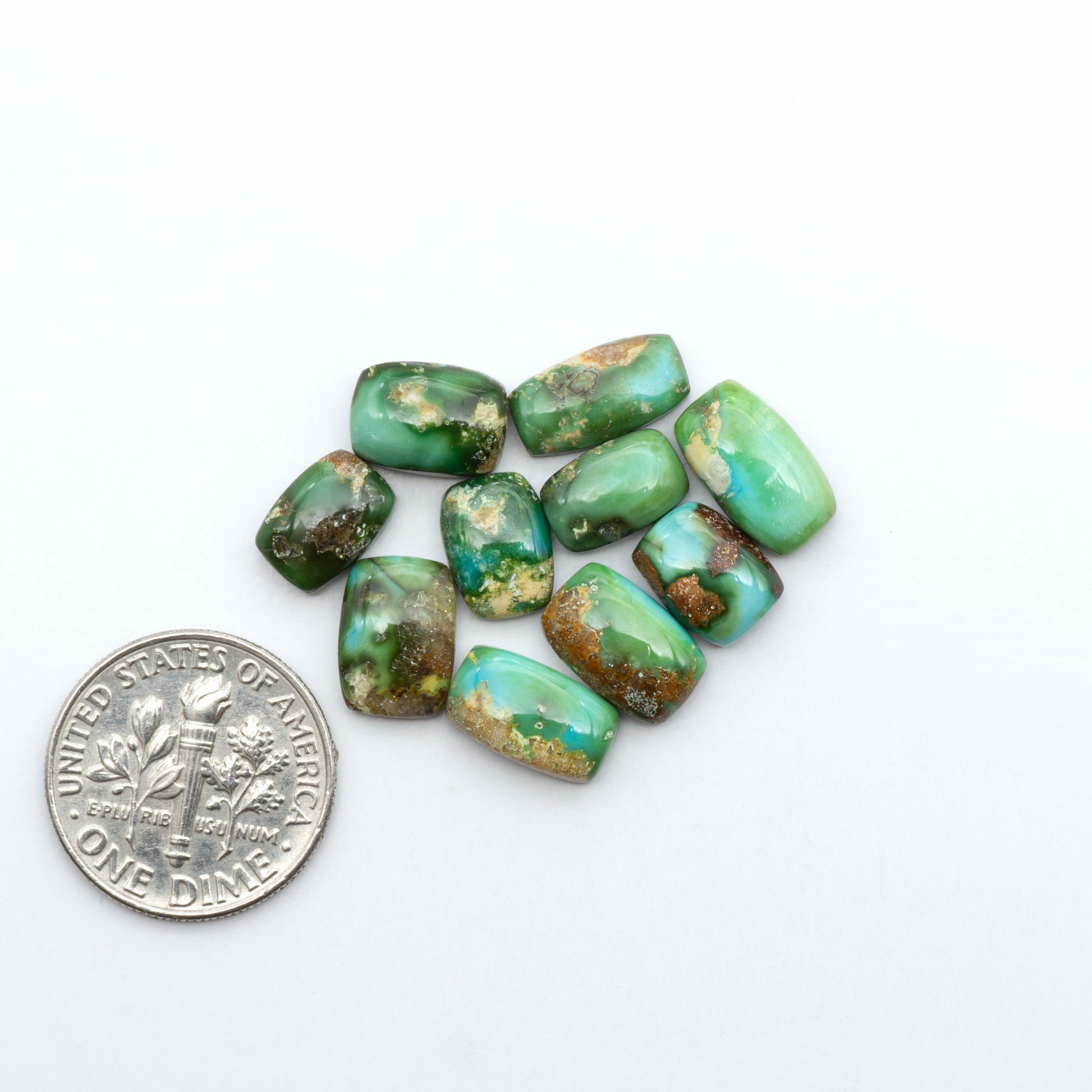Sonoran Mountain Turquoise cabochons, blue-green color with natural matrix, polished stones on a white background, with a US dime for scale
