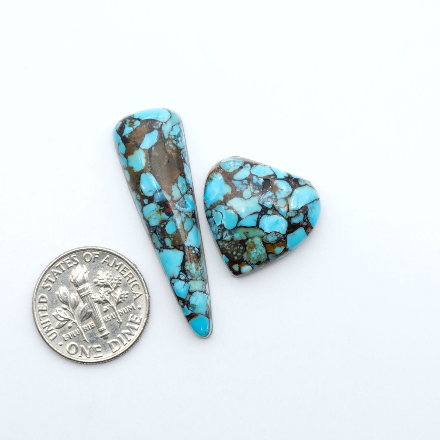 Pressed Turquoise nugget cabochons, composite material with a blue color and dark matrix on a white background, with a US dime for scale.