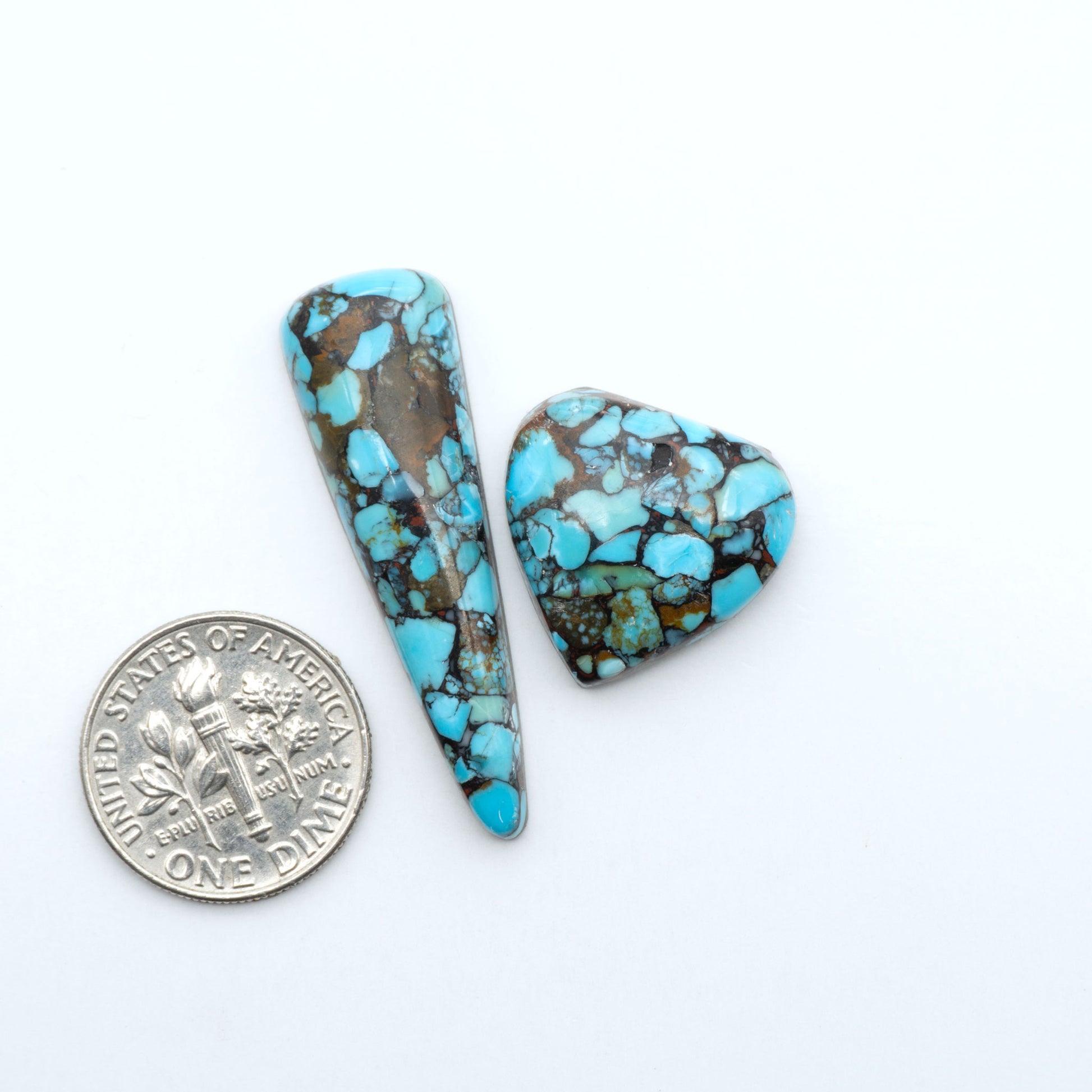Pressed Turquoise nugget cabochons, composite material with a blue color and dark matrix on a white background, with a US dime for scale.