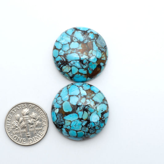 Pressed Turquoise nugget cabochons, composite material with a blue color and dark matrix on a white background, with a US dime for scale.