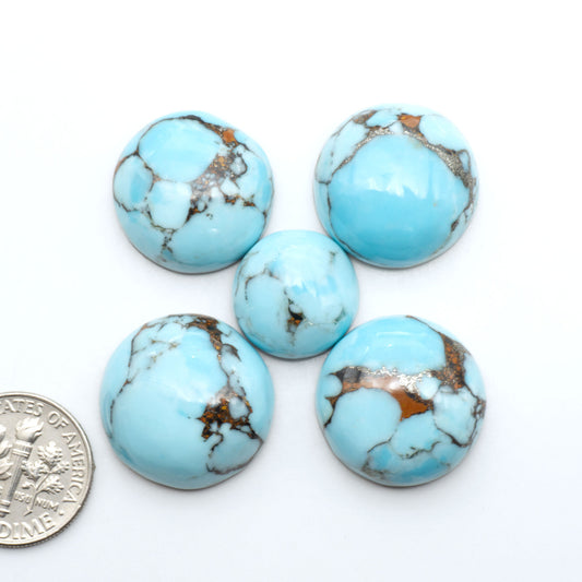 Pressed Turquoise nugget cabochons, composite material with a blue color and dark matrix on a white background, with a US dime for scale.
