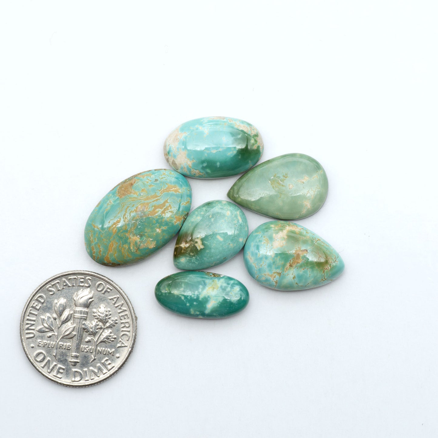 Royston Turquoise cabochons, blue-green color with natural matrix, polished stones on a white background, with a US dime for scale