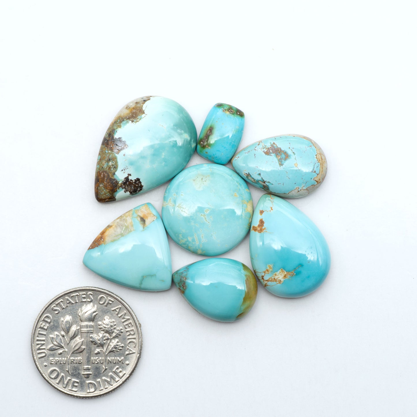 Royston Turquoise cabochons, blue-green color with natural matrix, polished stones on a white background, with a US dime for scale