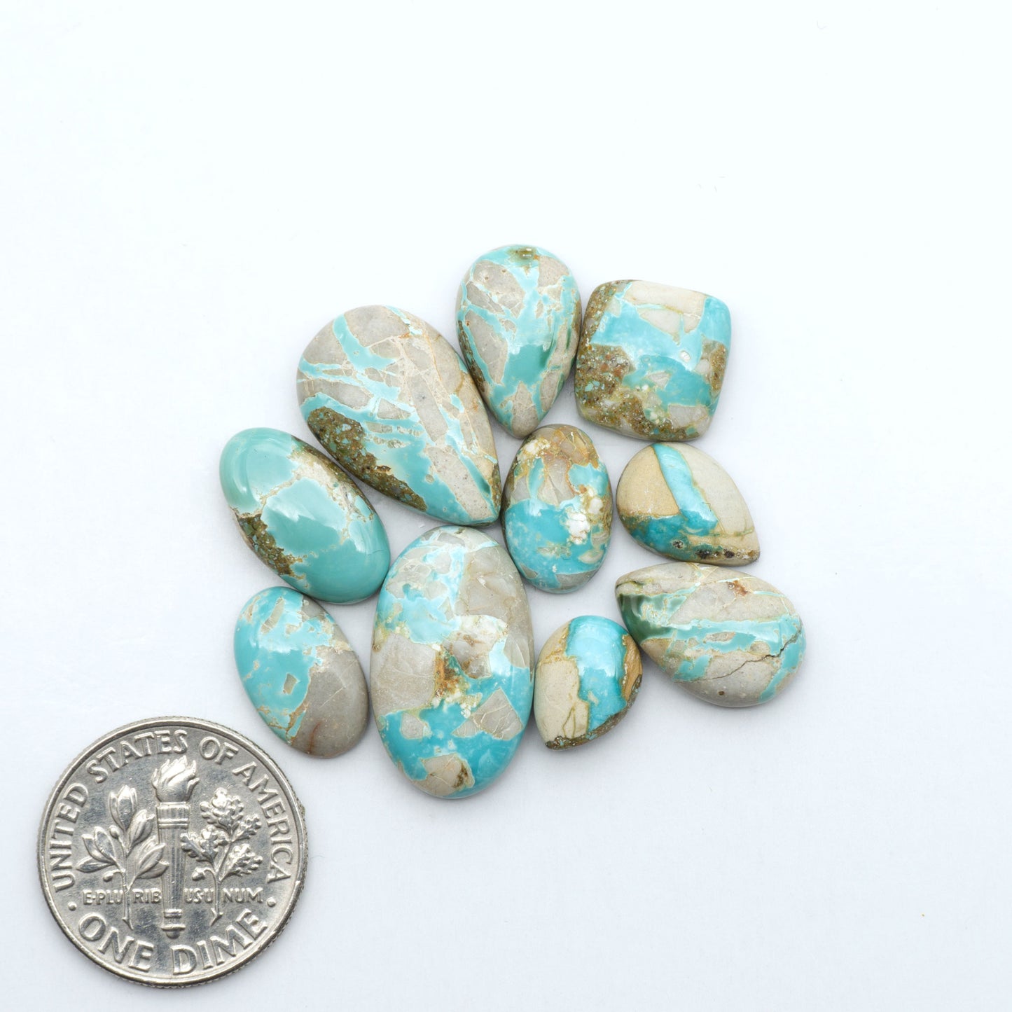 Royston Turquoise cabochons, blue-green color with natural matrix, polished stones on a white background, with a US dime for scale