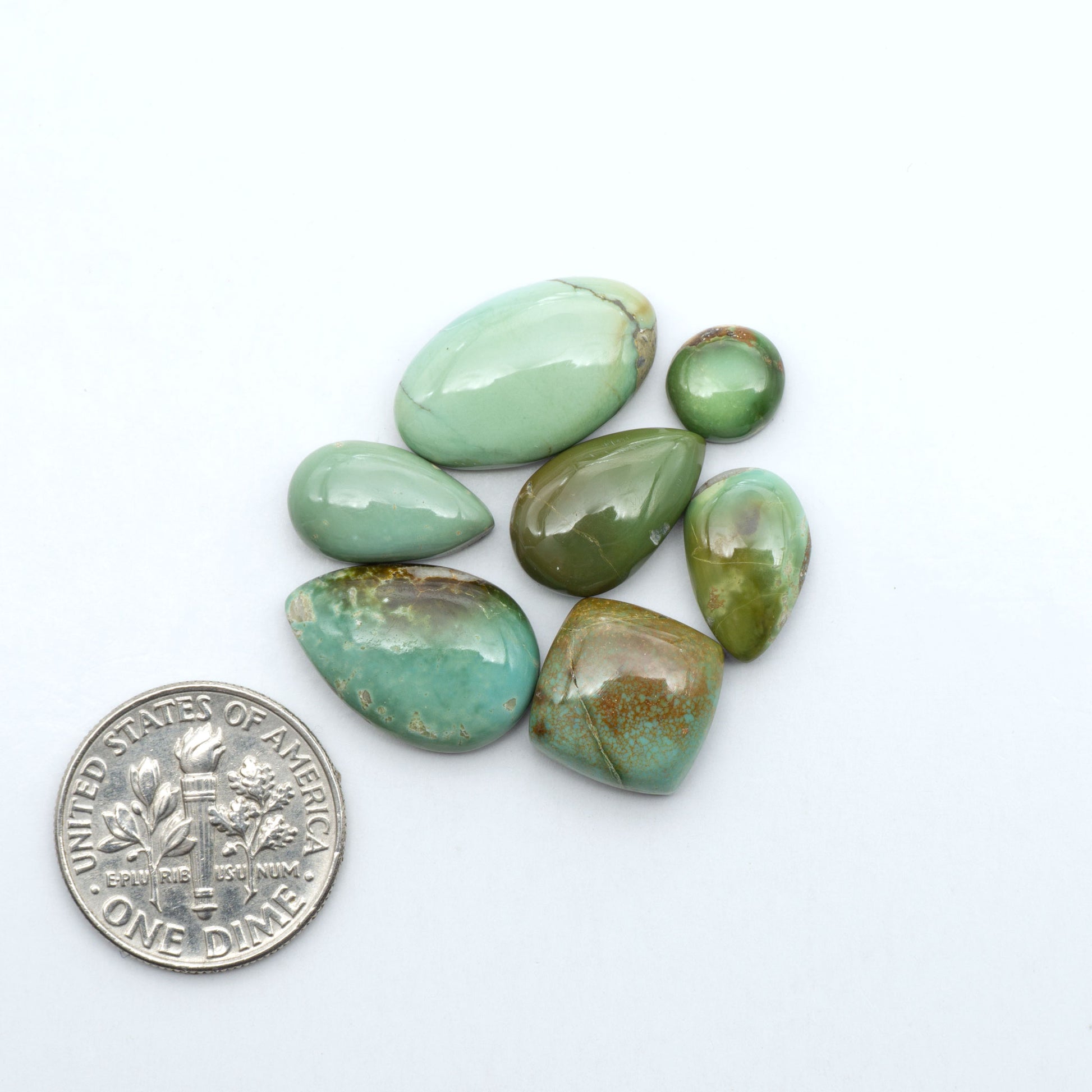 Royston Turquoise cabochons, blue-green color with natural matrix, polished stones on a white background, with a US dime for scale