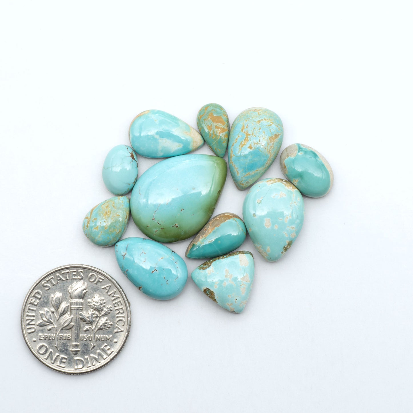 Royston Turquoise cabochons, blue-green color with natural matrix, polished stones on a white background, with a US dime for scale